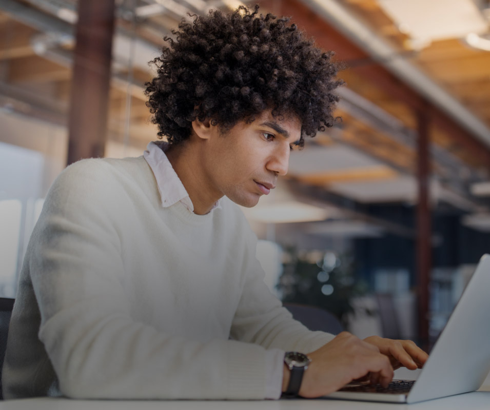 MAN AT OFFICE WORKING ON HIS LAPTOP