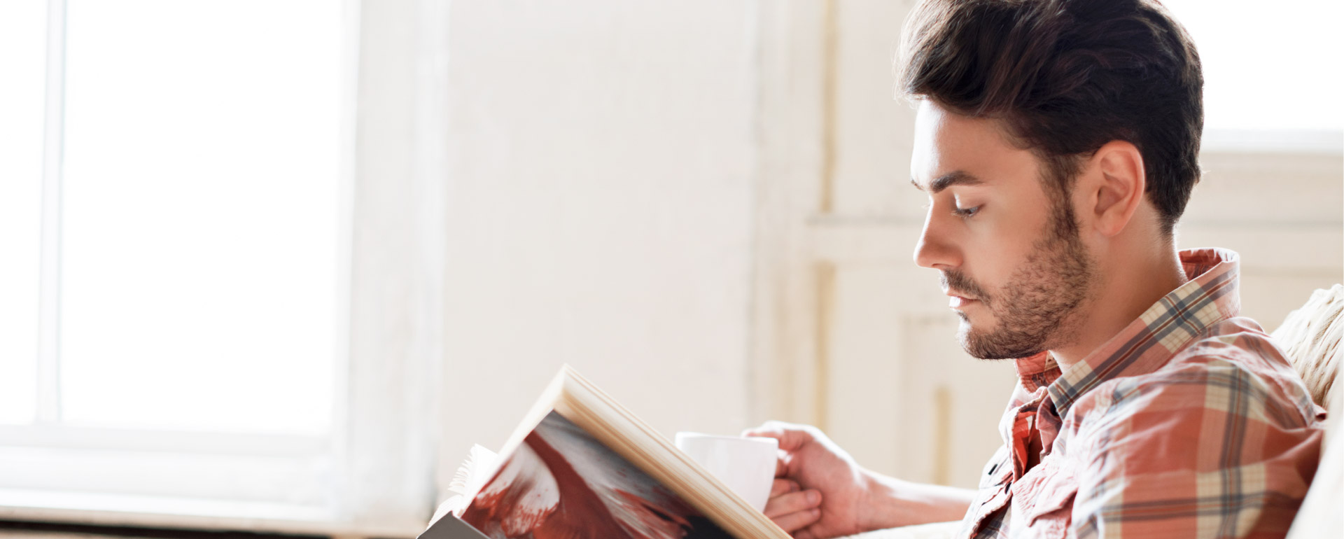 HOMME LISANT UN LIVRE DANS UN FAUTEUIL