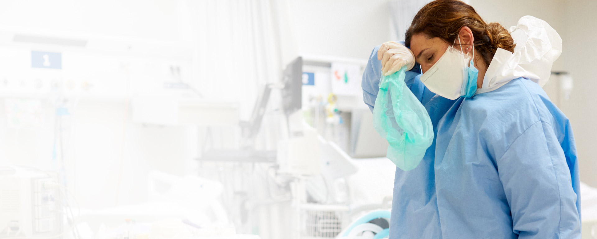 WOMAN IN SCRUBS WIPING HER FOREHEAD