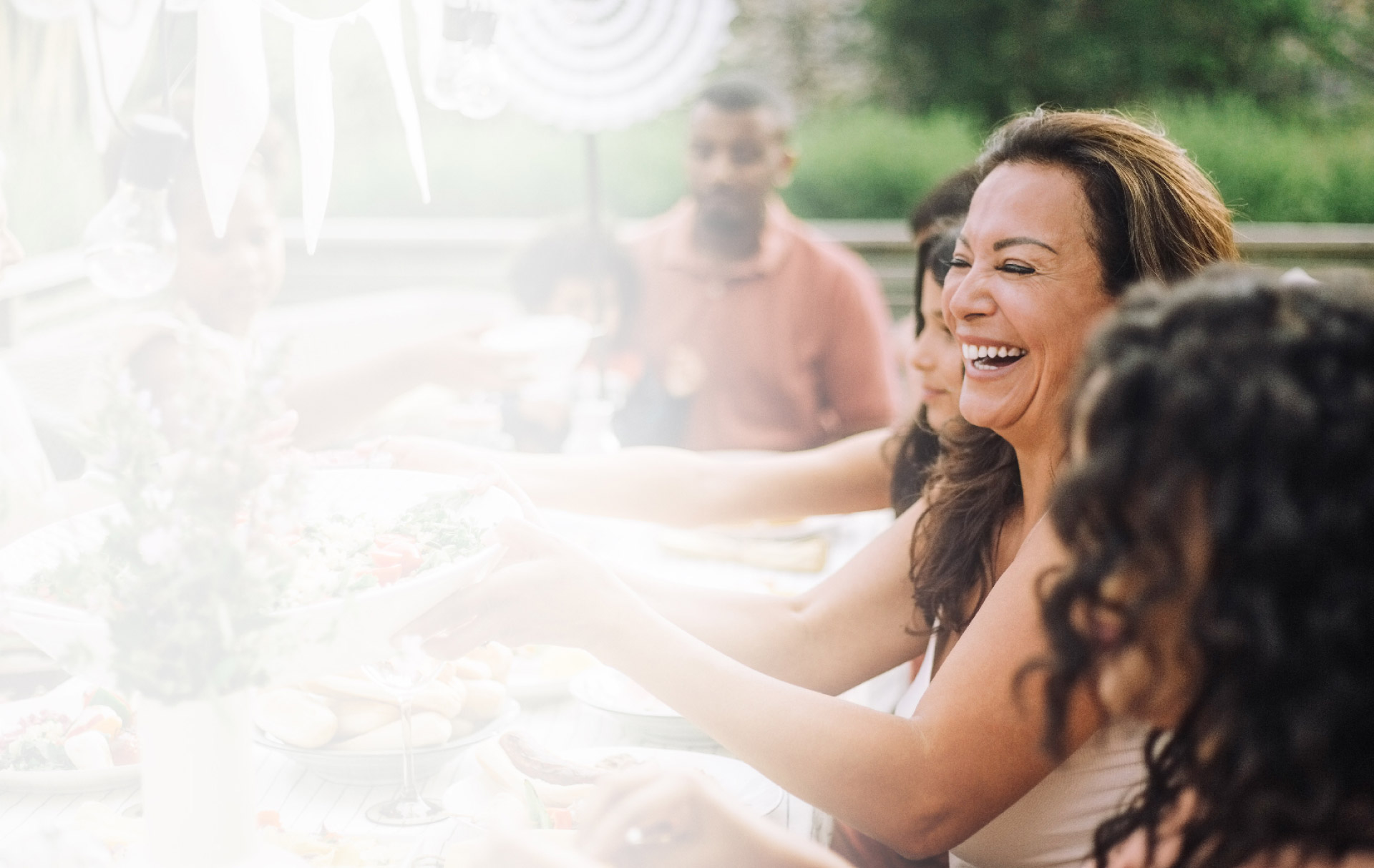 WOMAN LAUGHING AT DINNER WITH FRIENDS