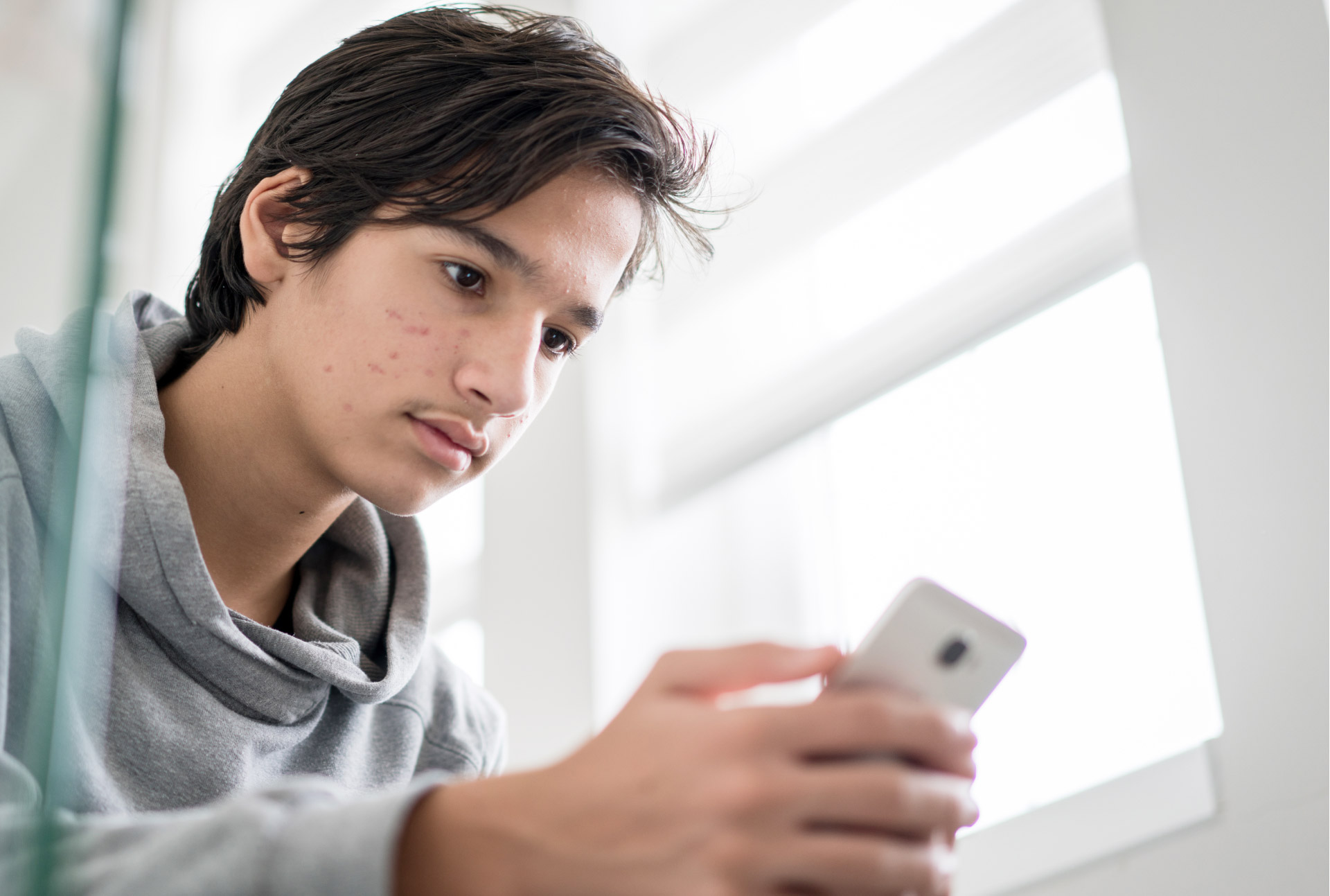 TEEN BOY LOOKING AT HIS CELLPHONE