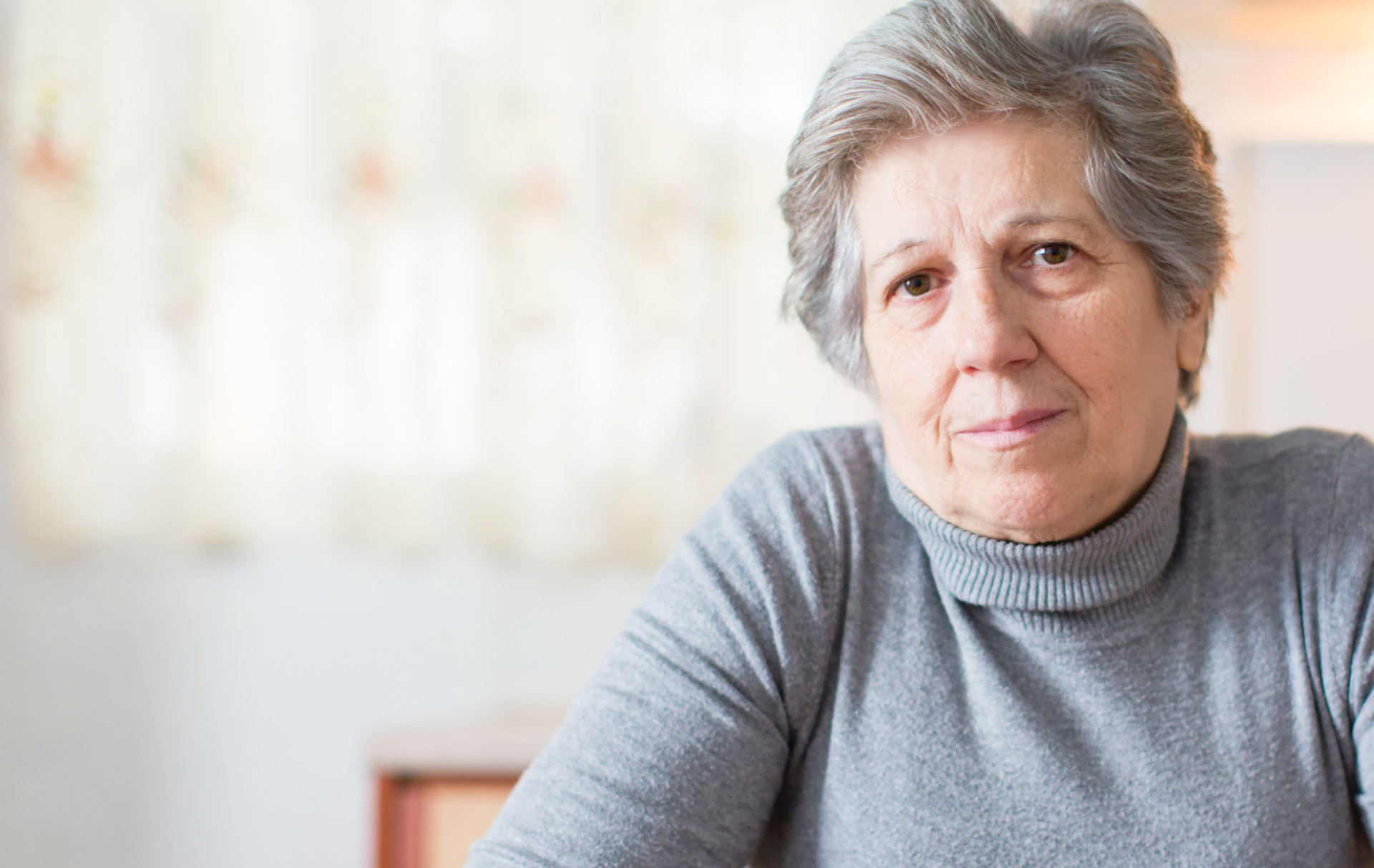 SENIOR WOMAN AT HOME LOOKING STRAIGHT AHEAD