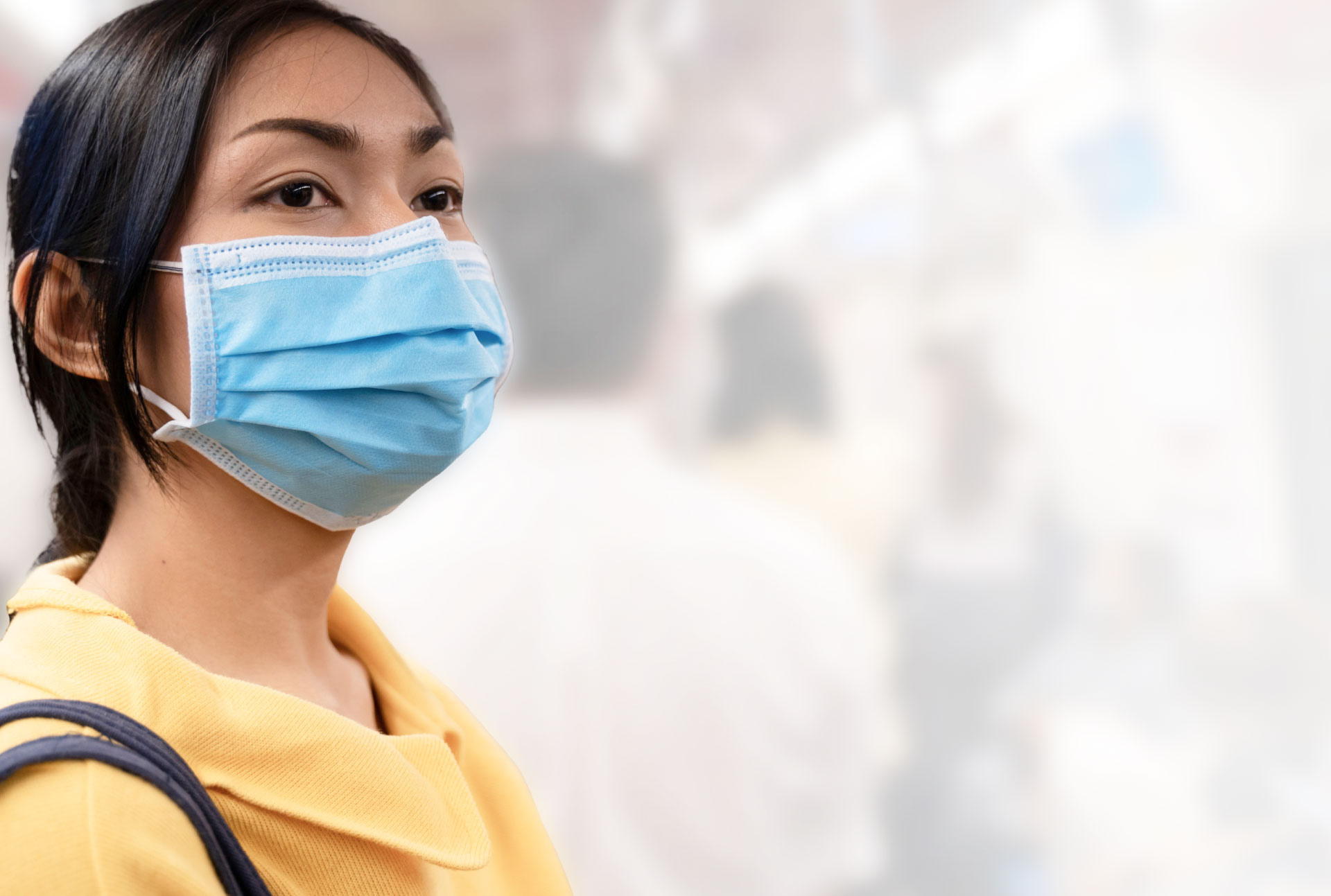 WOMAN WEARING HOSPITAL MASK ON A CITY STREET