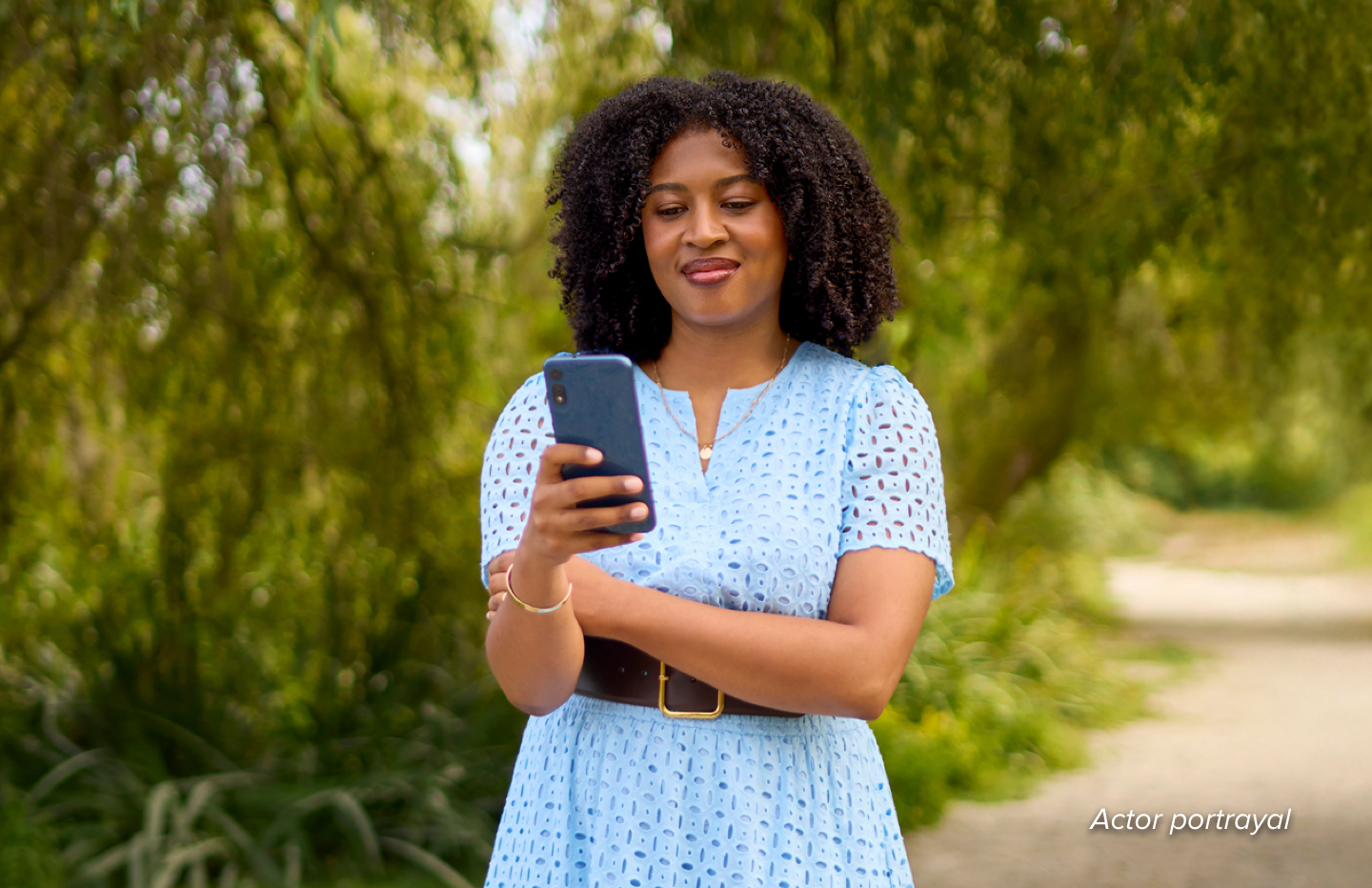 Woman standing in park looking at her phone.