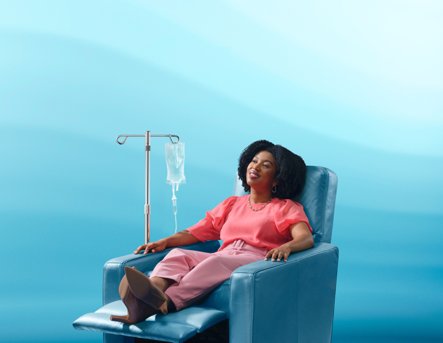 Female patient smiling and sitting in reclined chair during her IV infusion.