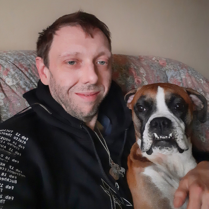 Jeffrey, VYEPTI® patient, sitting on his couch with his dog.